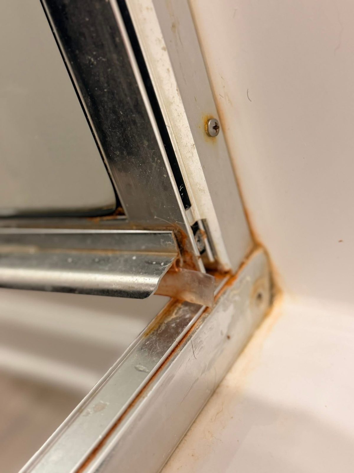 Before: rusted, grimy shower door track corner